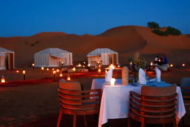 Mesa para dos con farolillos encendidos sobre las dunas de Merzouga al anochecer